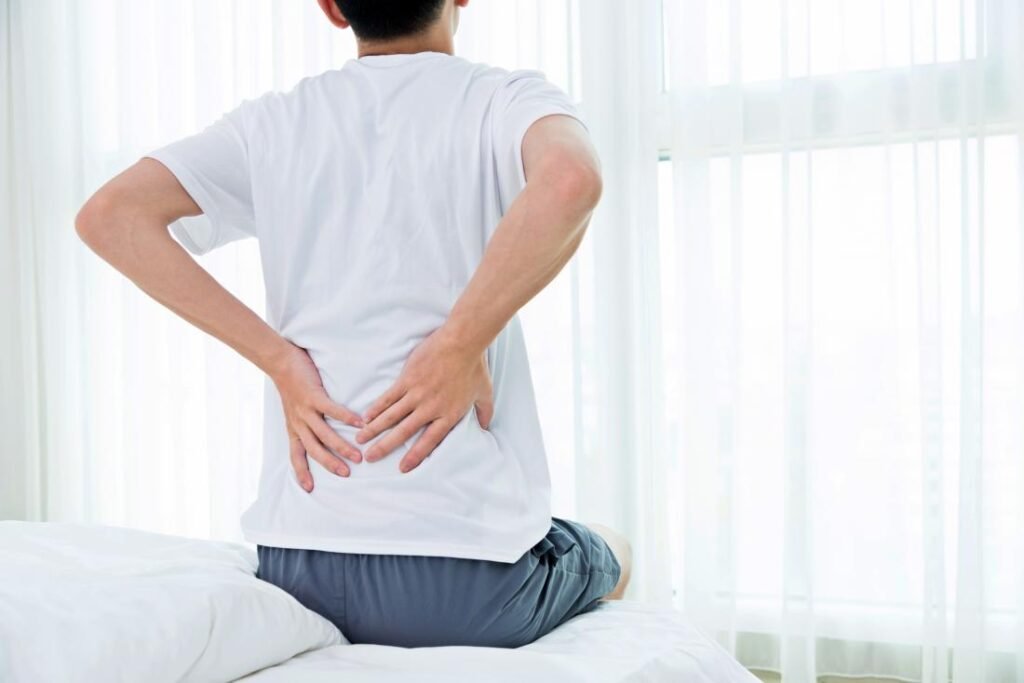 man-with-hip-pain-at-night-sitting-on-bed-holding-lower-back