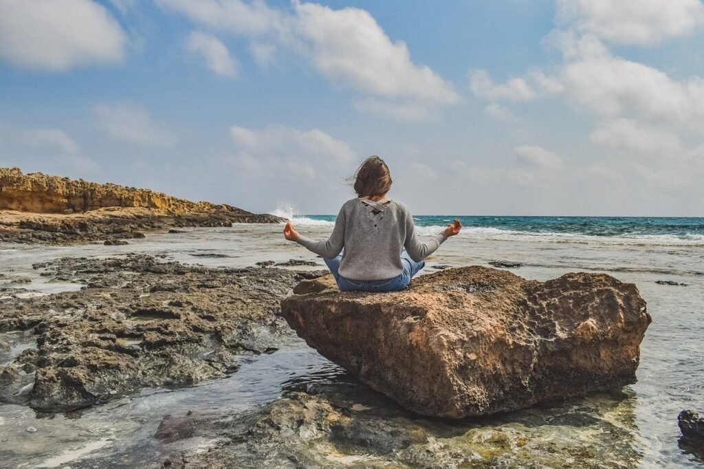 girl-practicing-meditation-on-rocky-beach